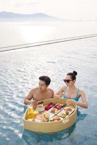 岘港Da Nang - Mikazuki Japanese Resorts & Spa的水中的男人和女人,带一盘食物