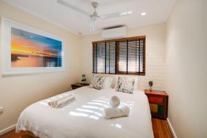 NightcliffTropical Boho Nightcliff Casinha 3BR 1.5BR的卧室配有白色的床和窗户。