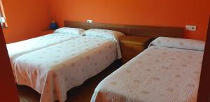 坎加斯-德奥尼斯费尔明住宿旅馆的橙色墙壁的客房内的三张床