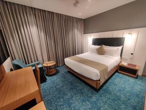AnkleshwarChryso Hotels Pvt Ltd的酒店客房配有一张床铺和一张桌子。