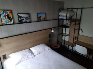 巴约讷巴约讷中心宜必思酒店的卧室配有白色的床和带照片的架子。