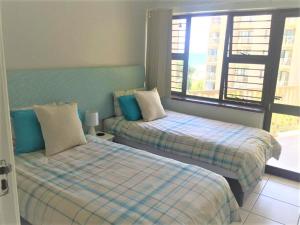 乌姆德洛蒂Umdloti Cabanas 21 Triplex的一间卧室设有两张床和窗户。