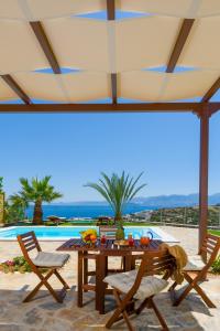 伊罗达Villa Calypso Elounda的一个带桌椅的庭院和一个游泳池