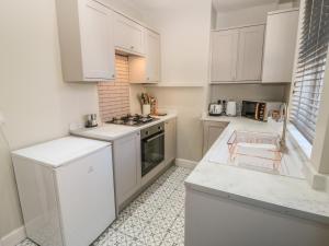 索厄比布里奇Calder Cottage的厨房配有白色橱柜和炉灶烤箱。