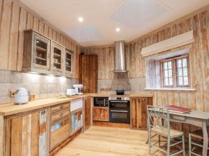 比尤利The Hen House的厨房配有木制橱柜、桌子和炉灶。