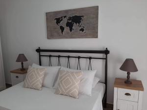 金尼昂Alisachni的卧室配有一张带白色枕头的床和一张墙上的地图