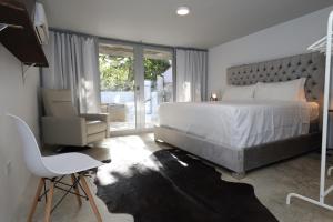 多拉多Viento Beach Lodge的卧室配有一张白色大床和一把椅子