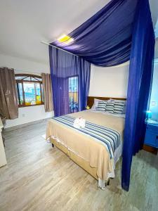 邦比尼亚斯Pousada Canto do Pescador的一间卧室配有一张蓝色天蓬床
