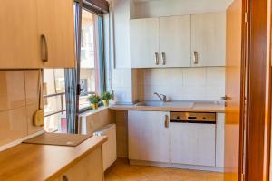 布加勒斯特Sunny & spacious place with breathtaking view的厨房配有白色橱柜、水槽和窗户。