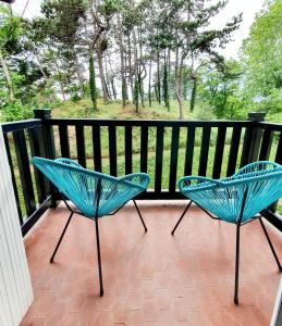 滨海伯内尔维尔Le bord de plage的阳台配有两把蓝色椅子,后方是树木