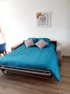 滨海伯内尔维尔Le bord de plage的一张带蓝色棉被和枕头的床