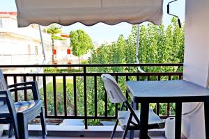阿马林索斯Το Κοράλι的阳台配有桌子和两把椅子,配有桌子和雨伞