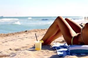 迈阿密海滩迈阿密海滩海岸套房公寓式酒店的躺在海滩上喝一杯的比基尼女人