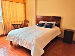 库斯科Hostal Ukumari Andino的卧室配有带蓝色枕头的大型白色床
