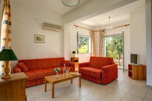 斯巴达利阿卡斯村公寓的客厅配有两张红色的沙发和一张桌子