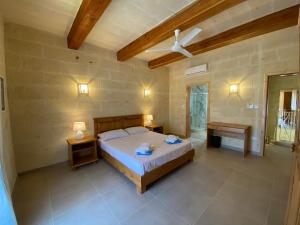 萨奈特Ta' Ganna Farmhouse的一间卧室配有床、两张桌子和风扇