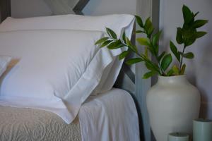 滨海波利尼亚诺Dimora Lilla的睡床旁的白色花瓶,上面有植物