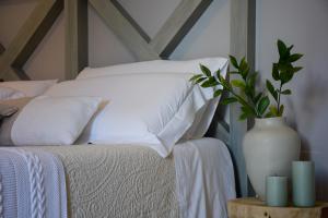 滨海波利尼亚诺Dimora Lilla的一张带白色枕头和桌子花瓶的床