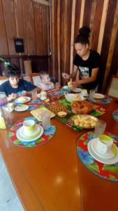 伊波兰加Canto do Sabiá PETAR Hospedagem Familiar的坐在餐桌旁吃饭的女人和两个孩子