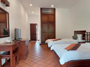 琅勃拉邦Villa Chitchareune 2的客房设有两张床、一张桌子和一台电视。