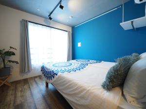 东京Luana Shibuya的一间卧室配有一张蓝色墙壁的床