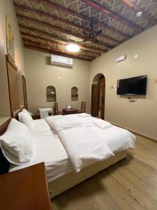 尼兹瓦Nizwa Heritage Inn的一间卧室配有一张大床和一台平面电视