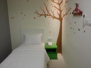 八打灵再也草莓园酒店的卧室配有一张床,墙上有一棵树