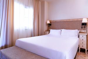 米哈斯Aparthotel Cordial Mijas Golf的卧室设有一张白色大床和一扇窗户。