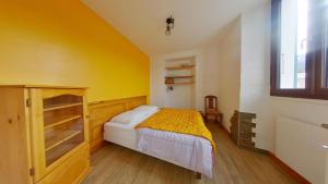 若西耶Appartement entier T4 à Jausiers的一间卧室设有一张床和黄色的墙壁
