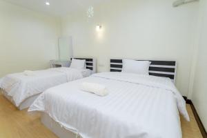 Ban Don KlangThai Guest House的配有白色床单的客房内的两张床