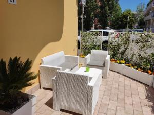 里米尼Residence Yellow的庭院配有白色藤椅和桌子