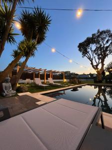 贡多马尔Villarit Porto的一个带桌子、棕榈树和灯的游泳池