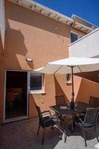 萨普伦纳拉Stermasi Apartments的庭院配有桌椅和遮阳伞。