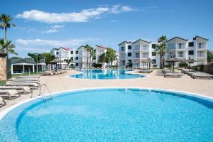 卡拉恩·布拉內斯Pierre & Vacances Menorca Cala Blanes的一个带椅子和公寓的大型游泳池
