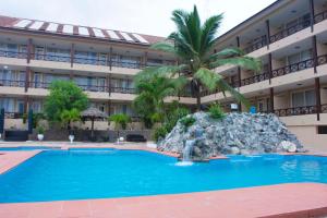 TeshiBest Western Plus Accra Beach Hotel的一座酒店,前方有一座游泳池和一棵棕榈树