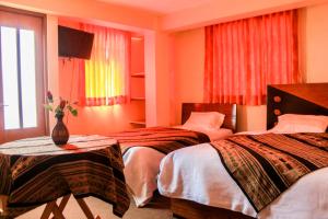 瓦拉斯Amazing Huaraz的酒店客房设有两张床和一张桌子上的花瓶