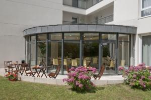 旺夫巴黎旺夫爱达格公寓式酒店 - 波特德夏特林的玻璃建筑,设有桌椅的庭院