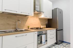 索伦托SYMPHONY HOUSE的厨房配有白色橱柜和不锈钢冰箱
