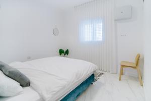 特拉维夫Yaffo Joy - Penthouse Apartment的白色卧室配有床和椅子