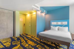 第比利斯ibis budget Tbilisi Center的一间卧室配有床,铺有蓝色和黄色的地毯