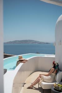 圣斯特凡诺斯Rocabella Mykonos Hotel的坐在游泳池旁椅子上的女人