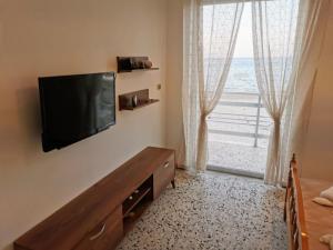 阿里克斯Anatolikos Rooms的卧室设有窗户,墙上配有平面电视。