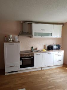 Haag2 Rooms cosy Apartment near Liechtenstein的厨房配有白色橱柜和炉灶烤箱。