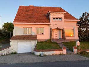 东代恩凯尔克Villa Friedolin heeft zicht op zee en duinen, in duinenreservaat, hot tub met jacuzzi en sauna met zeezichten te Oostduinkerke的粉红色的房子,设有白色车库