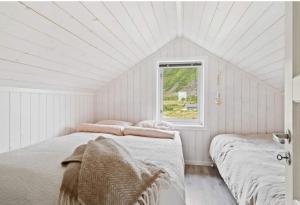 Gimsøy罗弗敦山林小屋的白色客房的两张床,设有窗户