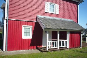 希尔克道夫Strandpark Sierksdorf H010的红色的房子,设有门廊和白色的围栏