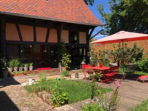 BourgheimB&B Le Lodge的一个带红色桌子和遮阳伞的庭院