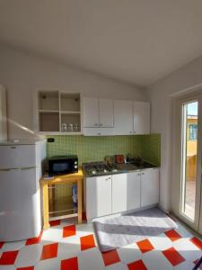 帕尔盖利亚Orizzonte Tropea的厨房配有白色橱柜,铺有红色和白色的地板。