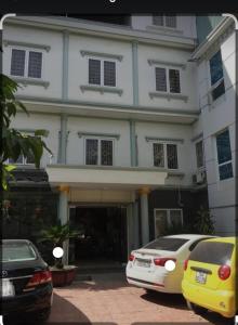 海防Motel TÂY HỒ的一座白色的建筑,前面有汽车停放