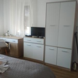 代姆延Kaptárkő Apartmanház的一间卧室配有书桌和大型白色橱柜